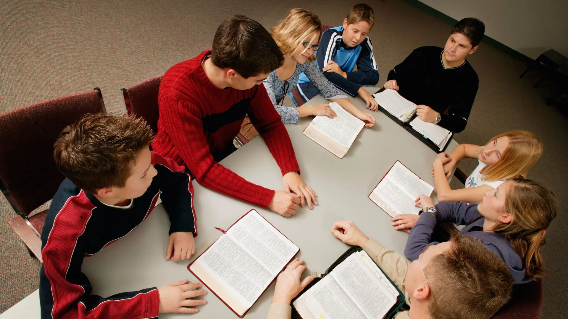 Youth group with a teacher reading the Bible during a church meeting